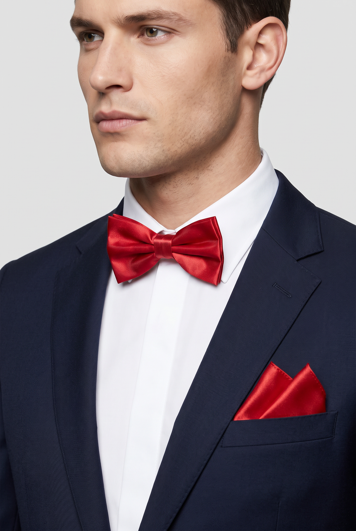 Men wearing a red satin bow tie and matching pocket square with a suit