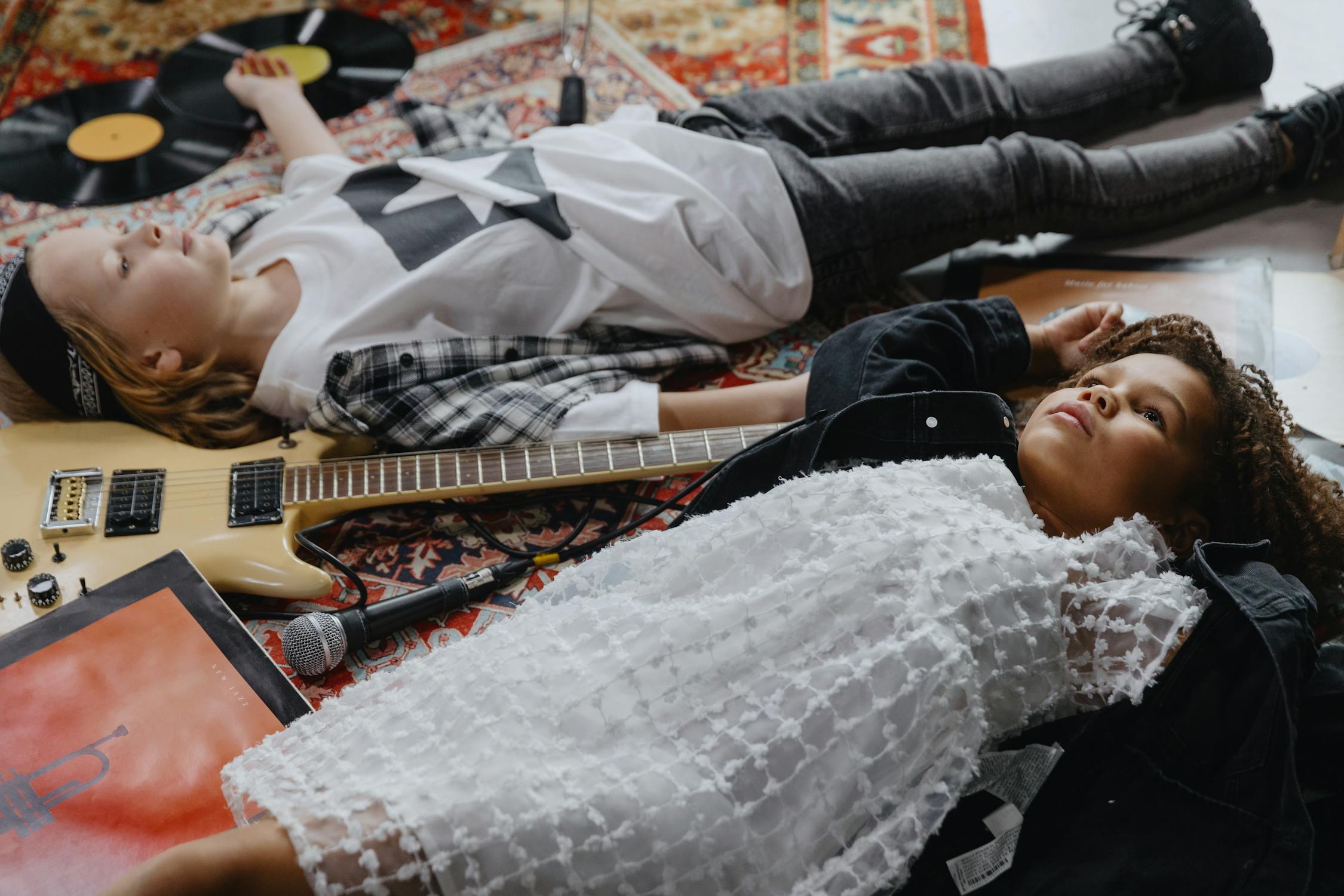 Two Stylish Kids in Vintage Clothes lying on a Carpet