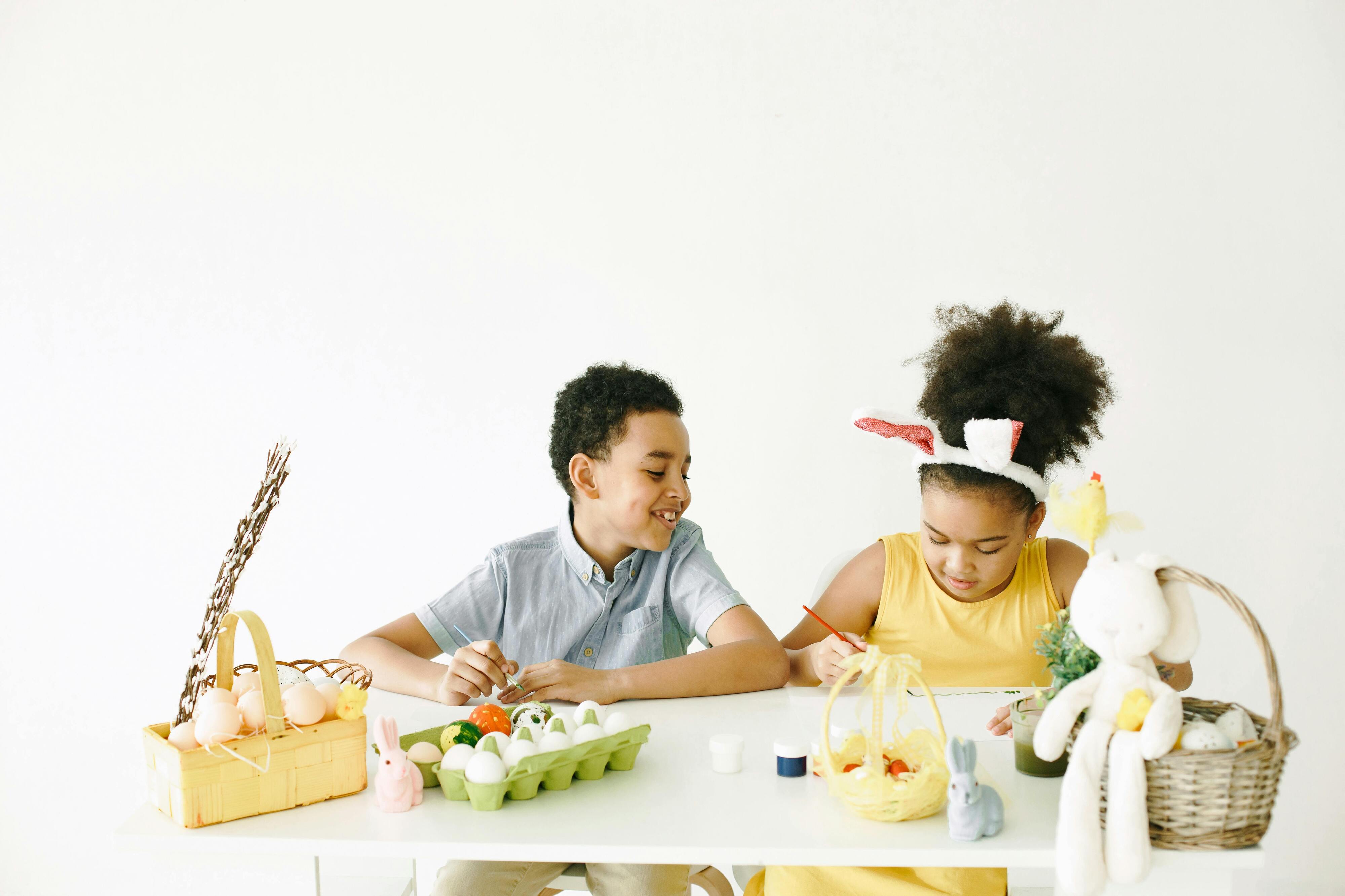 A girl and Boy Sitting Next to Each Other Decorating Easter Eggs