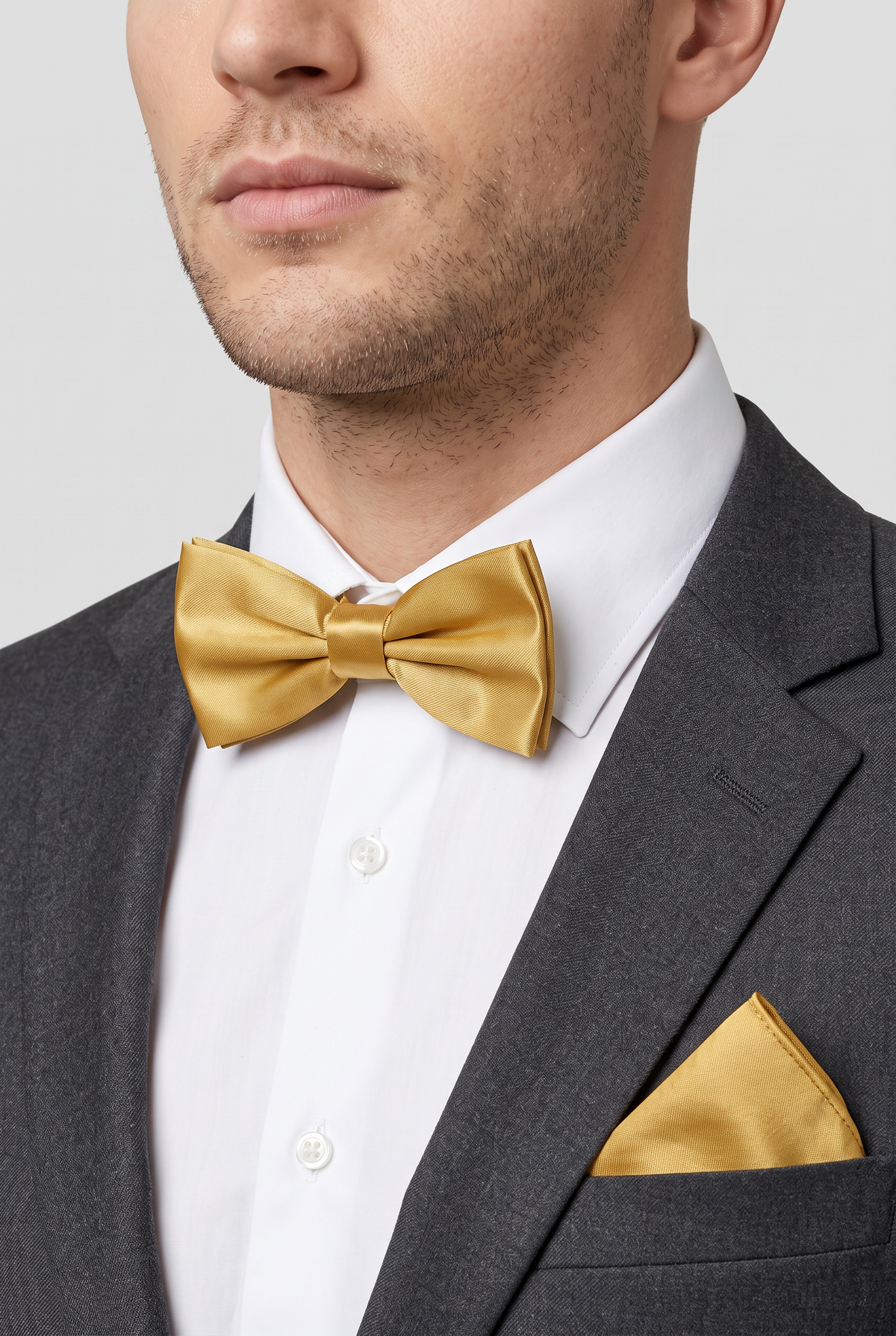 Men wearing a gold satin bow tie and matching pocket square with a suit