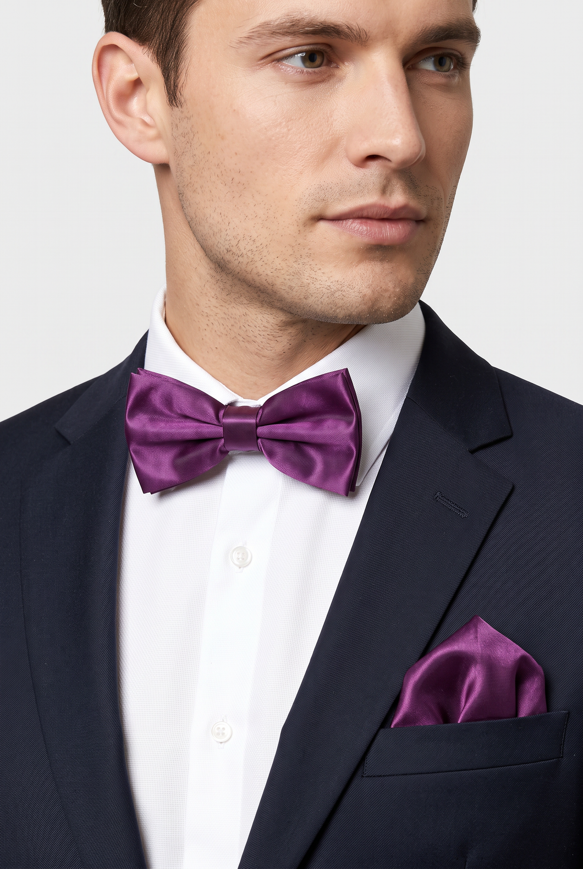 Men wearing a purple satin bow tie and matching pocket square with a suit